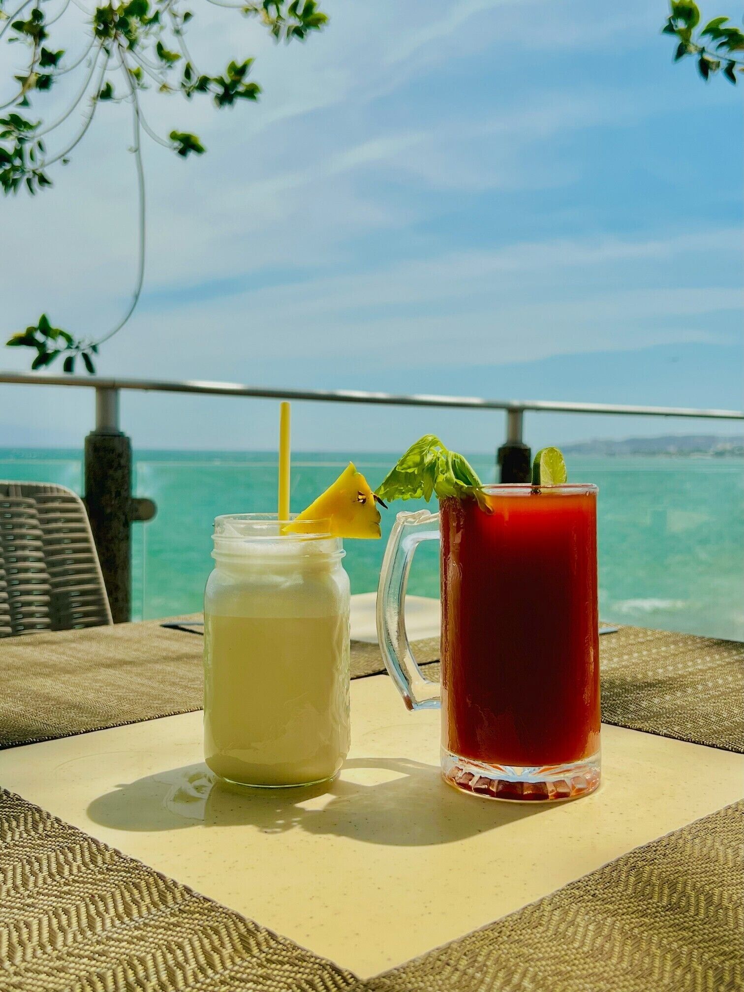 Two drinks on a table with a view of the sea.