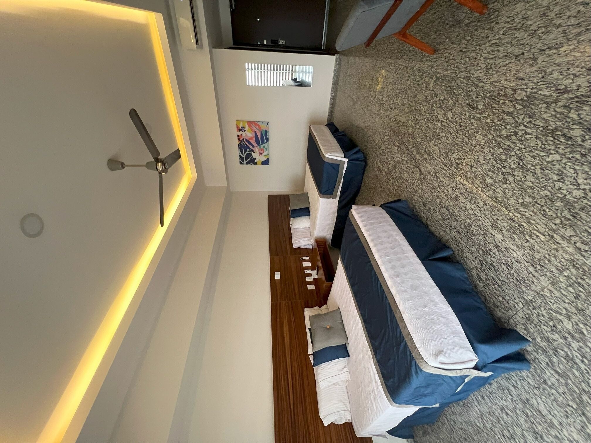 Une chambre d’hôtel moderne équipée d’un lit, d’un bureau, d’une chaise et d’un ventilateur de plafond.