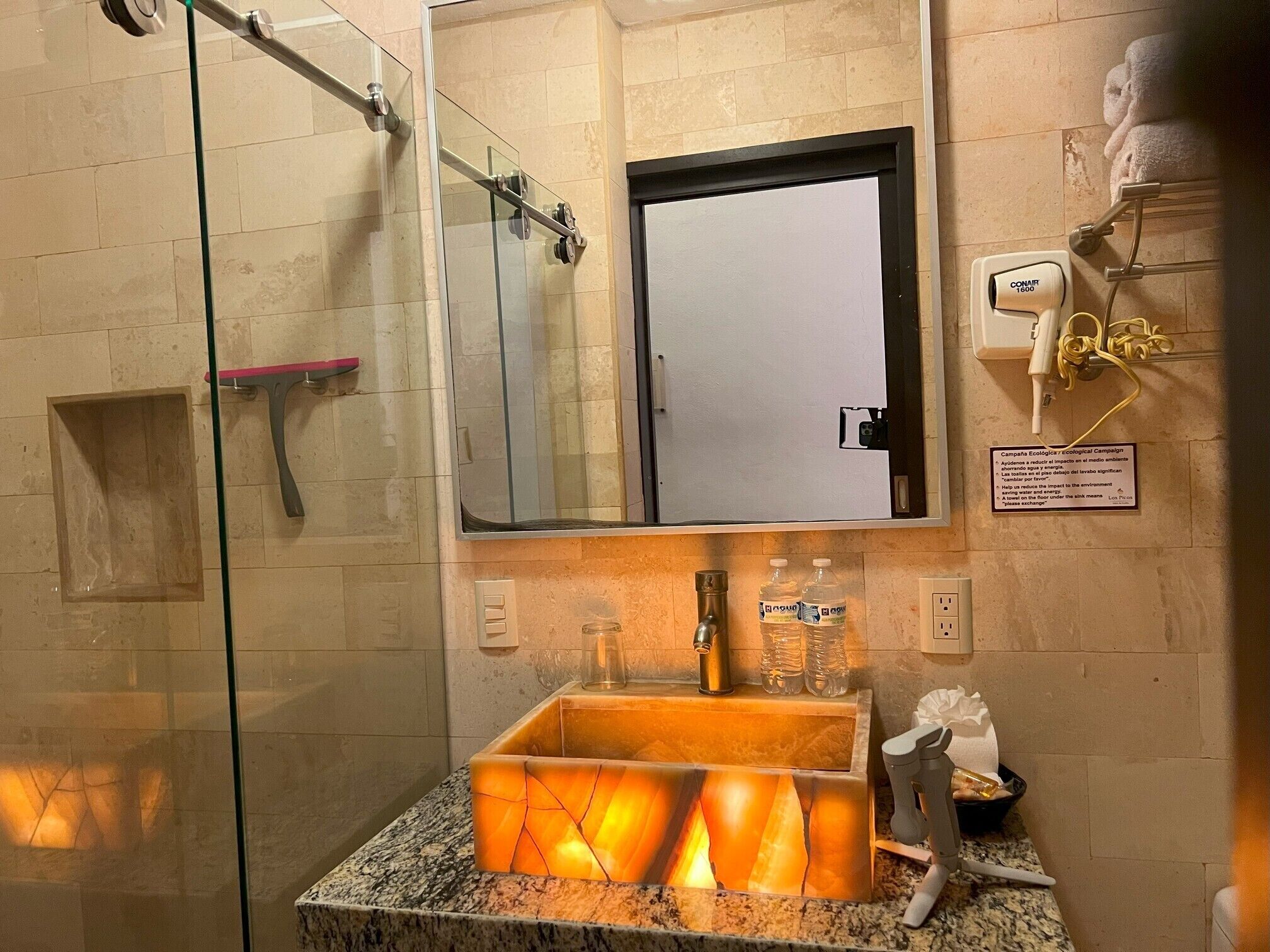 Une salle de bain avec une douche à parois de verre, un lavabo avec un miroir au-dessus et un porte-serviettes avec des serviettes.
