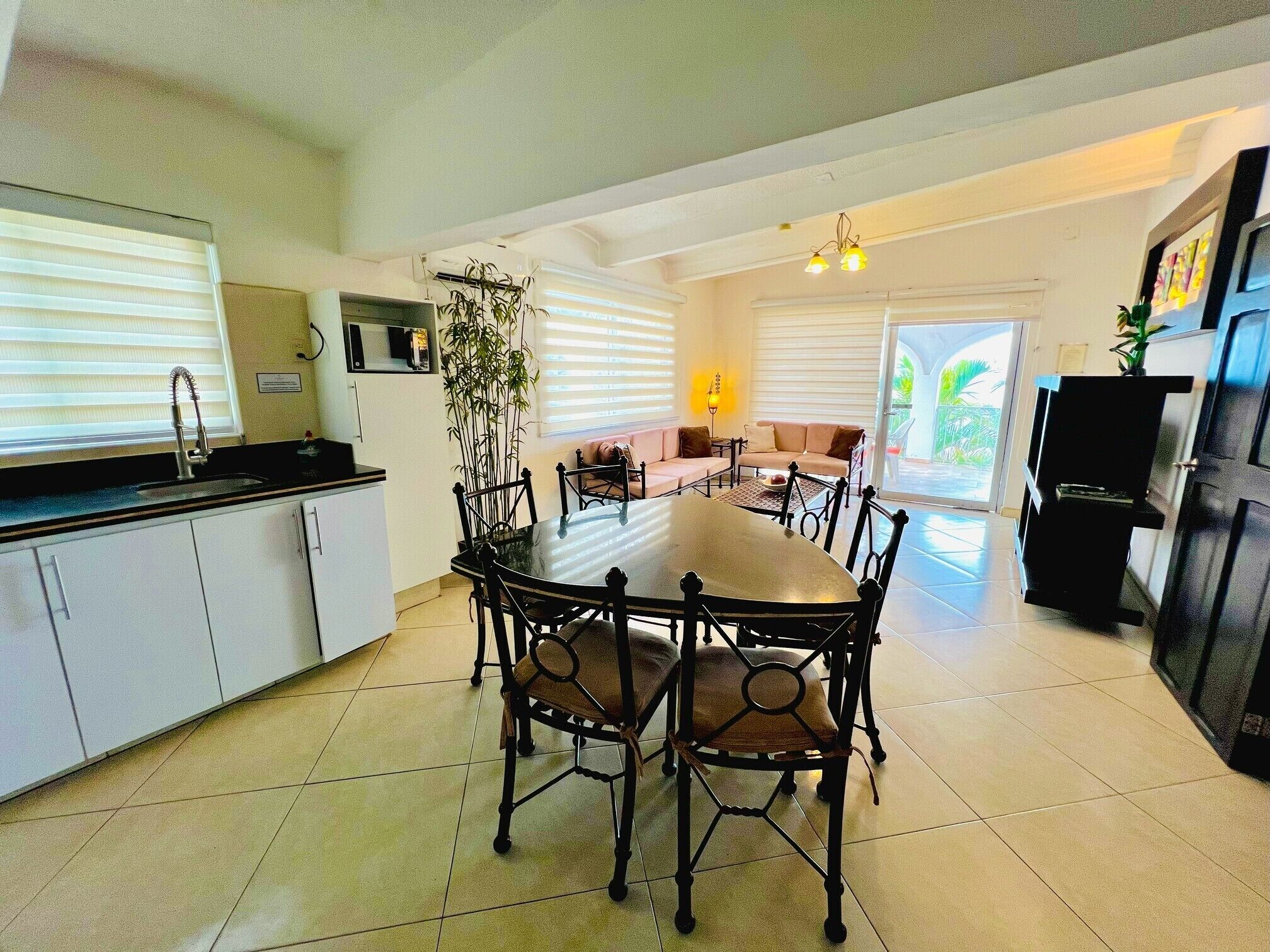 A modern kitchen with a dining area, white cabinets, and a large window.