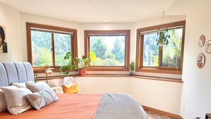 A bedroom with a bed, a window, a potted plant, and a wall decoration. - Remodeled basement in Corvallis, surrounded by forest and trails! (Corvallis)
