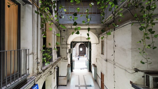 A narrow alleyway with tiled flooring, a metal railing on one side, and a building entrance at the end. - House in the heart of Naples: comfort, style and perfect location (Napoli)