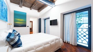 A bedroom with a bed, a painting, a TV, and a balcony with curtains. - House in the heart of Naples: comfort, style and perfect location (Napoli)