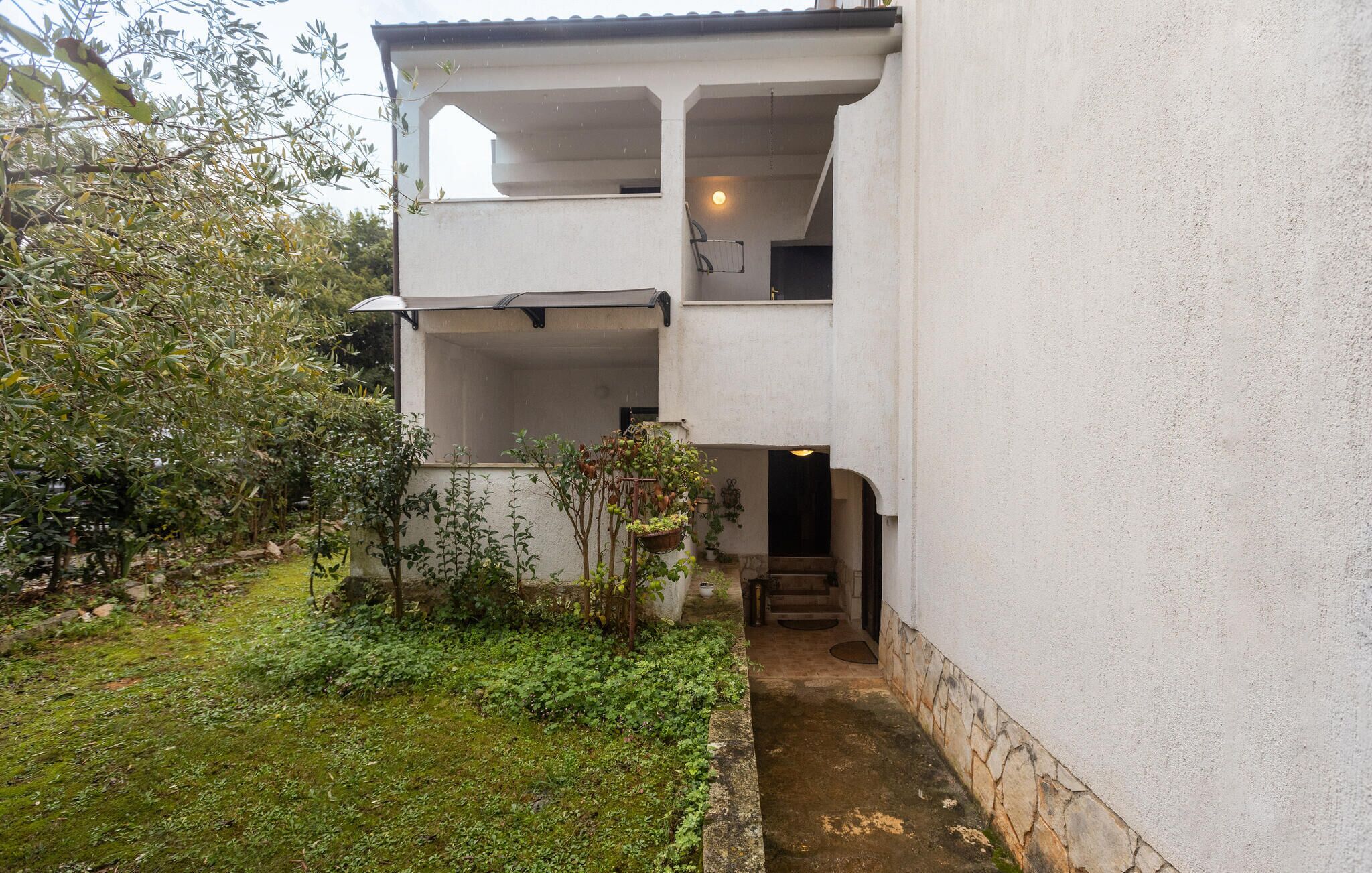 Un bâtiment à deux étages doté d’un espace extérieur couvert et d’un petit jardin.