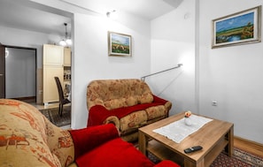 Una habitació amb un sofà, una taula amb un comandament a distància i un quadre al mur.