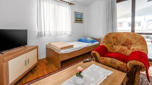 A room with a bed, a television, a sofa, and a window with curtains.