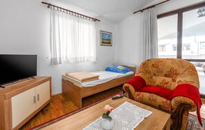 A room with a bed, a television, a sofa, and a window with curtains.