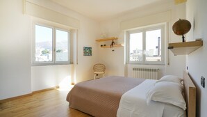 Una camera da letto con un letto grande, due finestre, un termosifone e una sedia.