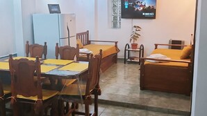 Un saló amb zona de menjador, un televisor penjat a la paret i una planta en test.