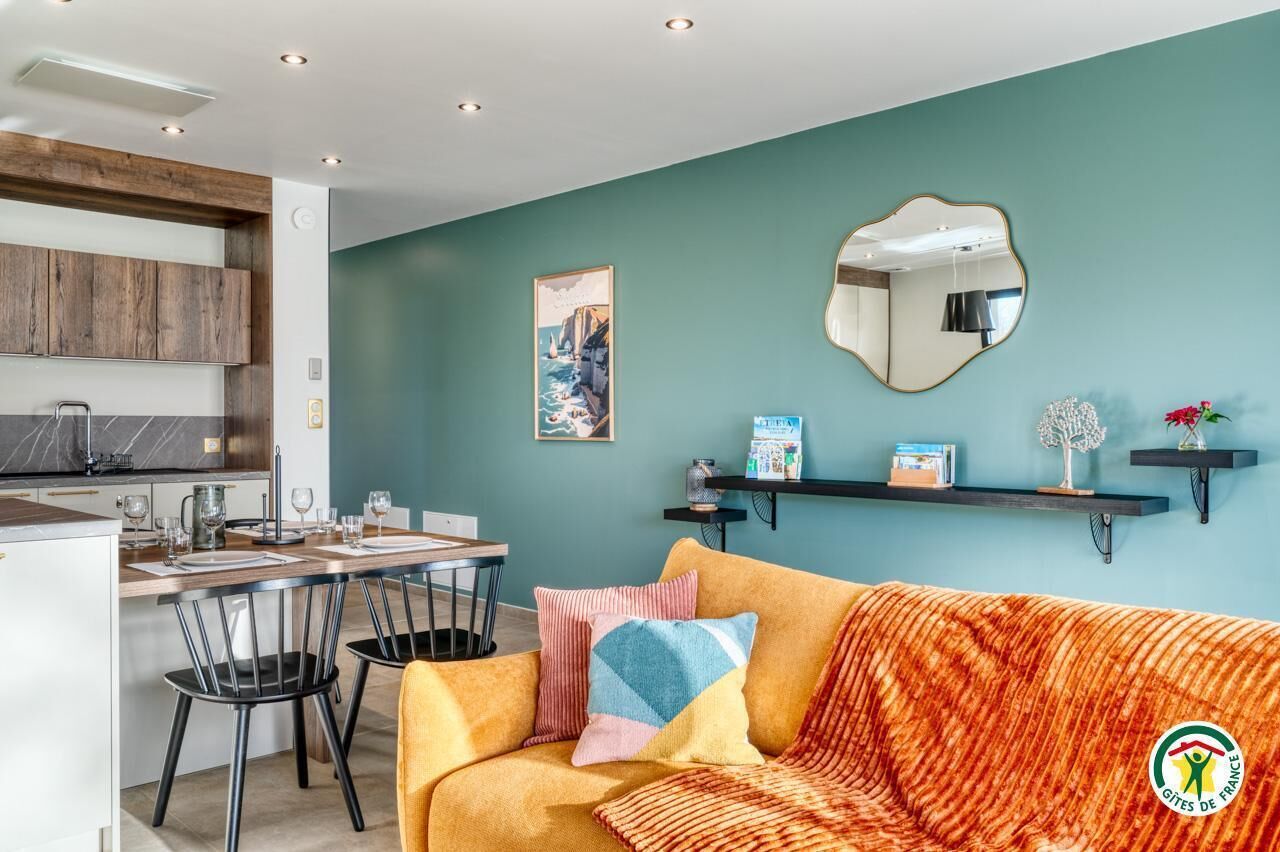 Un espacio habitable moderno con cocina, comedor y sofá con cojines coloridos.