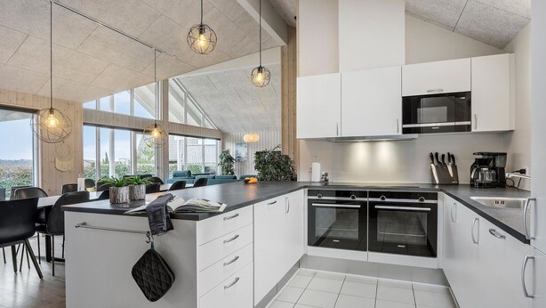 Une cuisine moderne avec des armoires blanches, des appareils en acier inoxydable et des luminaires suspendus.