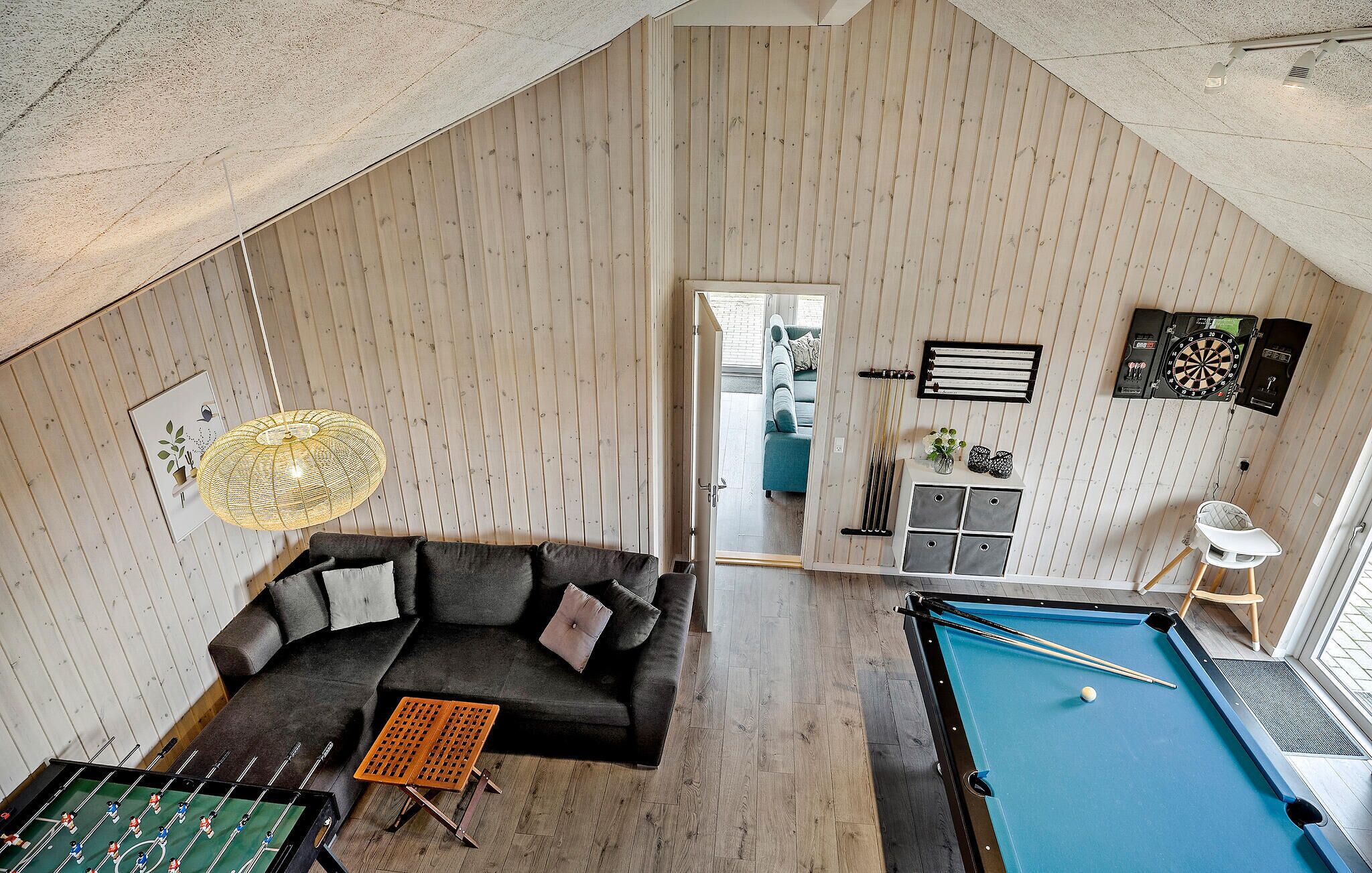 Ein Loft-Zimmer mit Pooltisch, einer Couch und einem Esstisch.