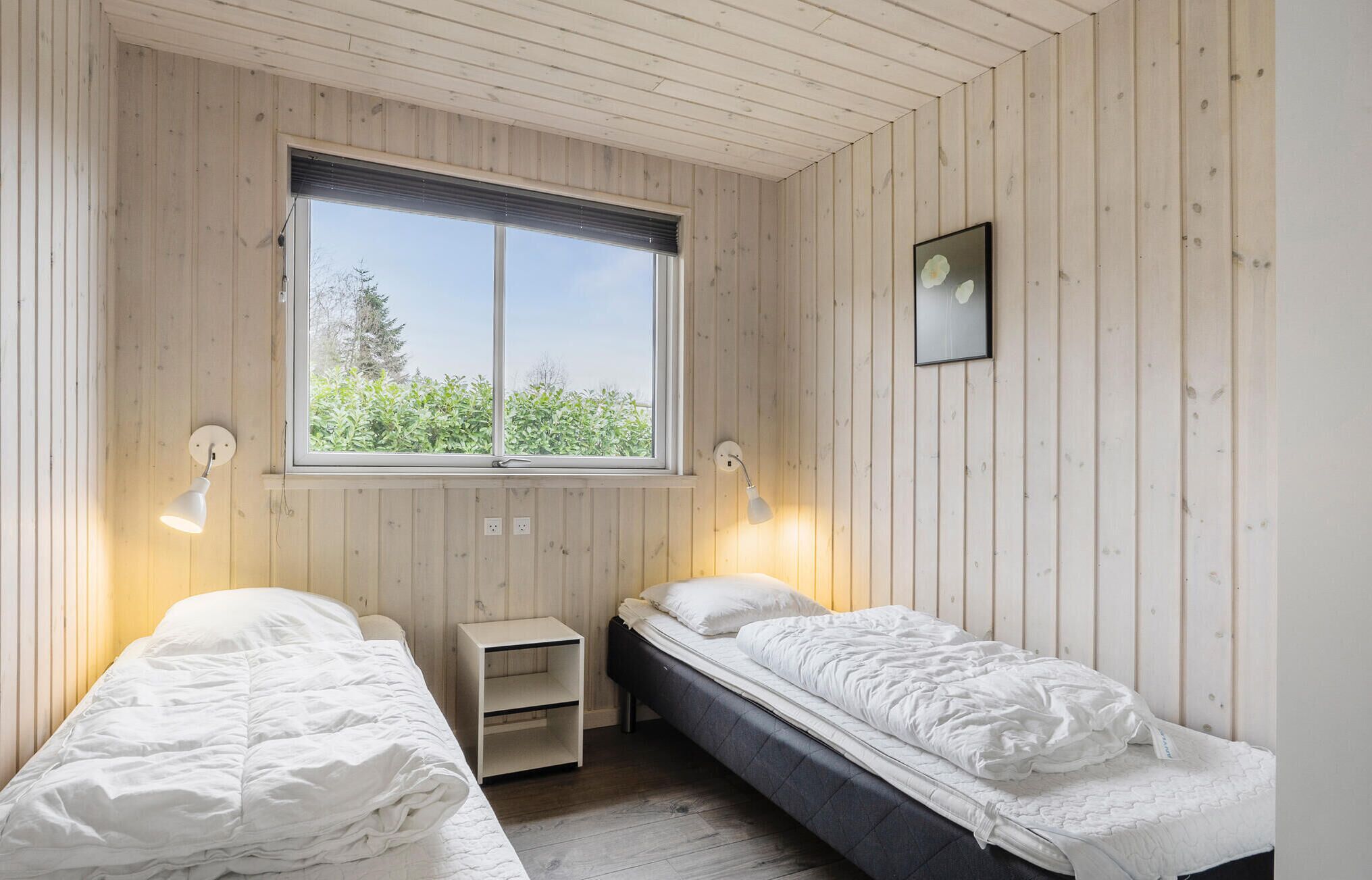 A bedroom with two beds, a window, and a picture on the wall.