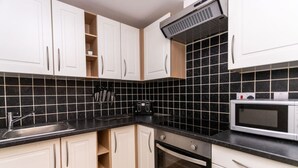 A modern kitchen with white cabinets, black tiles, a stainless steel sink, a toaster, and a microwave. - Contractor*Long Stays Discounts*Parking (Bristol)