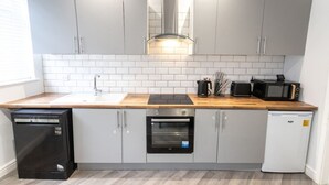 Una cocina moderna con armarios grises, encimera de madera, horno empotrado, lavavajillas y microondas.