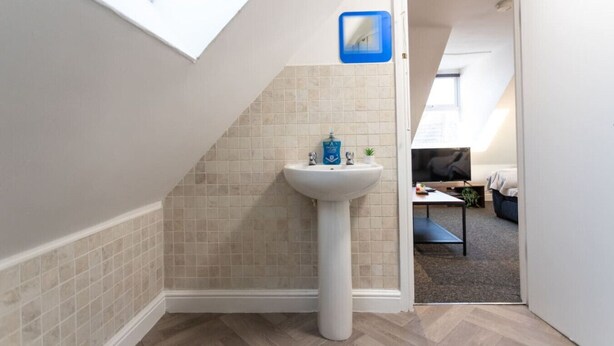 A narrow hallway with a white pedestal sink, beige tiled walls, and a small window. - Contractor*Long Stays Discounts*Parking (Bristol)