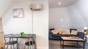 A modern living room with a dark grey sofa, patterned cushions, a wooden coffee table, and a dining area with a black table and chairs. - Contractor*Long Stays Discounts*Parking (Bristol)