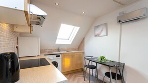 A compact kitchen with a built-in washing machine, a small dining table with two chairs, and a skylight above the sink. - Contractor*Long Stays Discounts*Parking (Bristol)