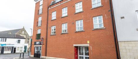 A red brick building with multiple windows and a red door.