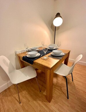 A dining table set with plates, glasses, and cutlery, flanked by white chairs, with a floor lamp in the background. - Central Location*Long Stays Discounts*Wyvern (Swindon)