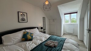 A bedroom with a bed, a hanging light fixture, a window, and a radiator. - Bolehyde House Long Stay Discounts Free Parking (Swindon)