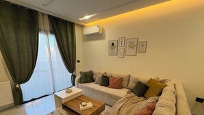 Ett vardagsrum med en beige soffa, ett soffbord i trä och en mönstrad matta.