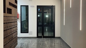 En modern hall med ett marmorgolv, en väggpanel i trä och en glasdörr.