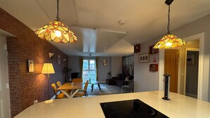 A modern kitchen with a central island, pendant lighting, and a dining area with chairs and a table.
