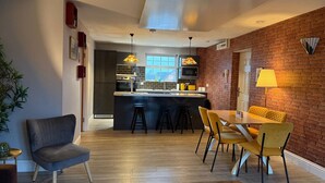 A modern kitchen with a central island, bar stools, and a dining area with yellow chairs.