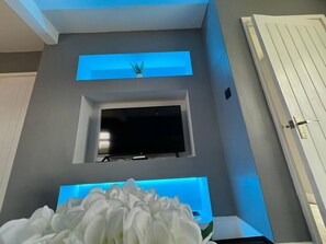 Enjoy a comfortable stay in this stylish room featuring a flat-screen TV and a beautiful floral arrangement.