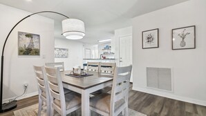Un comedor con una mesa y sillas de madera, una lámpara colgante y obras de arte en las paredes.