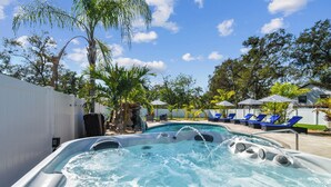 Un área de hidromasaje con piscina, sillas de descanso y palmeras.