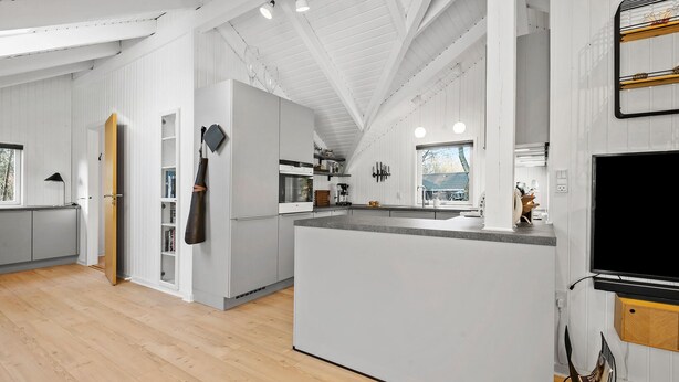 A modern kitchen with white cabinetry, a central island, and a large window providing natural light. - Amazing home in Ansager with WiFi (Ansager)