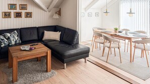 A modern living room with a black leather sofa, a wooden coffee table, and a dining area with a round table and chairs. - Amazing home in Ansager with WiFi (Ansager)