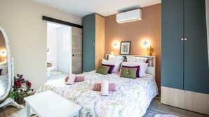 A bedroom with a bed, bedside table, dresser, and an air conditioning unit.