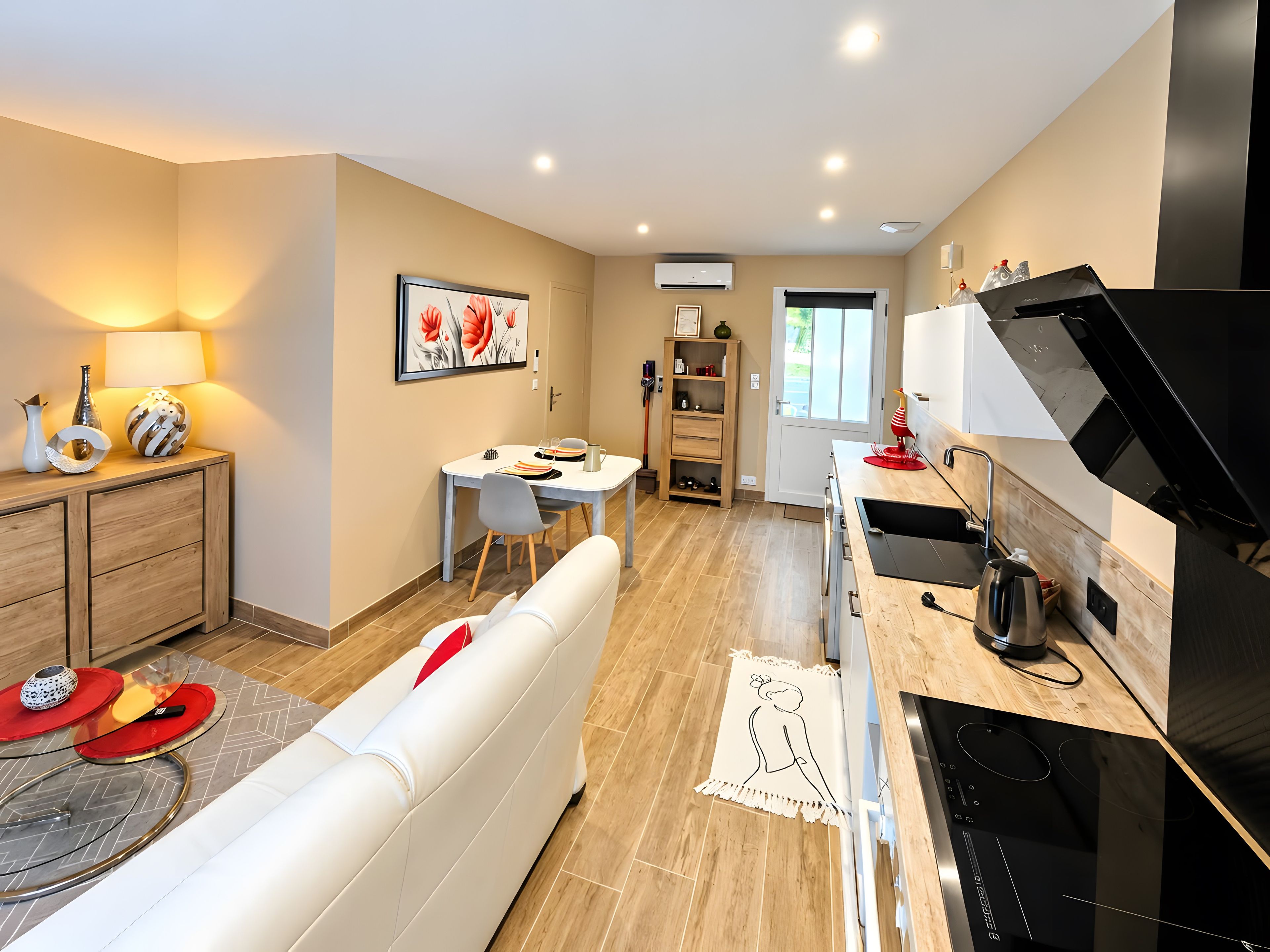 A modern kitchen with a black stove, a dining area with a table and chairs, and a living area with a white sofa.