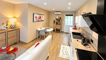 A modern kitchen with a black stove, a dining area with a table and chairs, and a living area with a white sofa.