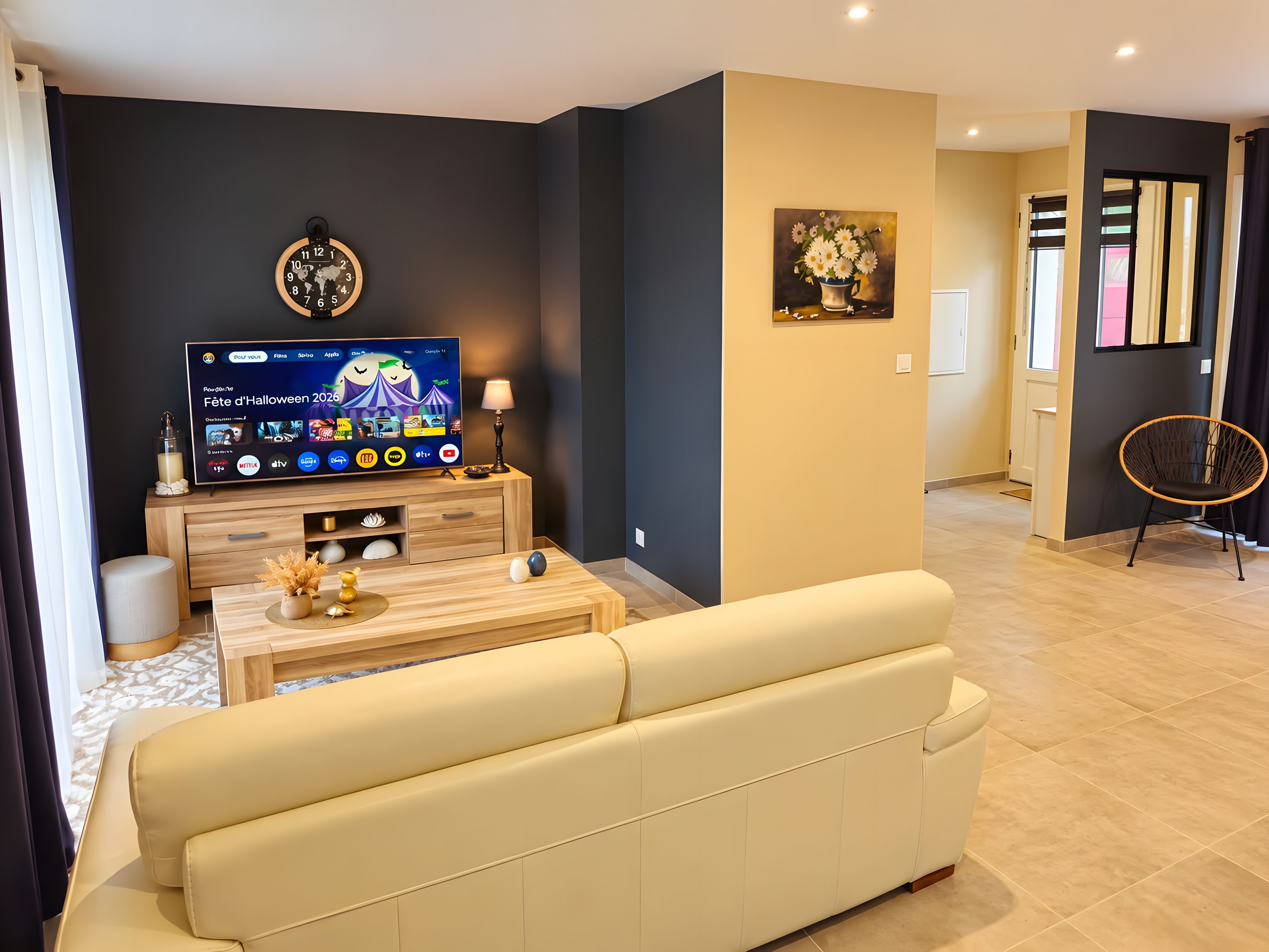 Een moderne woonkamer met een flatscreen televisie, houten meubels, een bank en een schilderij aan de muur.