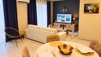 Ein modernes Wohnzimmer mit einer Couch, einem Esstisch und einem Fernseher.
