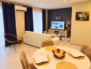 Een moderne woonkamer met een bank, eettafel en televisie.