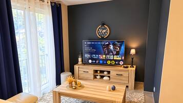 A modern living room with a flat-screen TV, a sofa, a coffee table, and a decorative wall clock.
