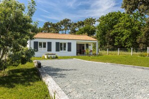 A single-story house with a tiled roof, a gravel driveway, and a fenced yard.