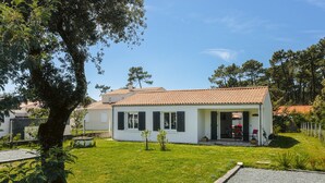 Une maison à deux étages, avec un toit en tuiles, une véranda et une pelouse bien entretenue.