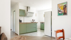 Une cuisine moderne avec des meubles de couleur verte, une table à manger en bois et une chaise.