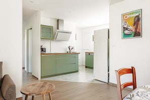 A modern kitchen with green cabinets, a wooden dining table, and a chair.
