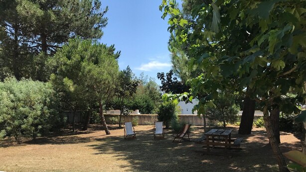 A backyard with a paved patio, a wooden bench, and a metal chair. - Holiday Home 'Maison À 8min De Plage Giraudière' with Private Terrace and Private Garden (Le Grand-Village-Plage)