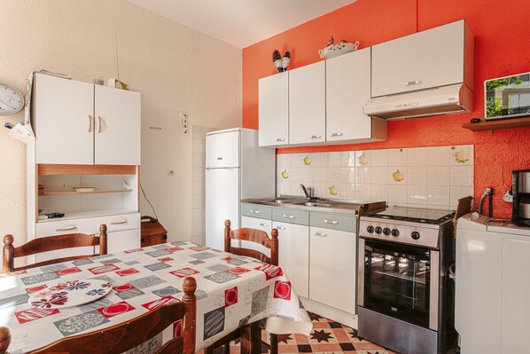 A compact kitchen with a dining table, chairs, a stove, and cabinets.