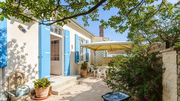 A courtyard with a table and chairs, a potted plant, and a small table with a tray. - Peaceful Holiday Home with Private Courtyard – Close to Beaches and Shops in Saint-Trojan (Saint-Trojan-les-Bains)
