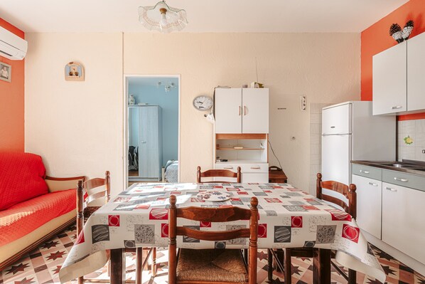 A compact kitchen with a dining table, chairs, and a refrigerator.