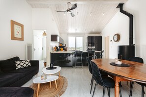 Moderni keittiö, jossa on ruokailutila, musta sohva ja puinen ruokapöytä.